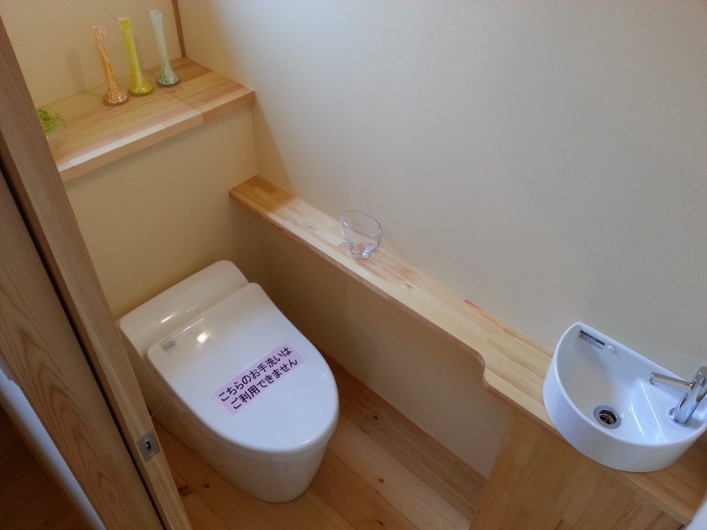 背面収納に手洗いカウンター収納。タンクレストイレを設置した天然木のトイレ空間