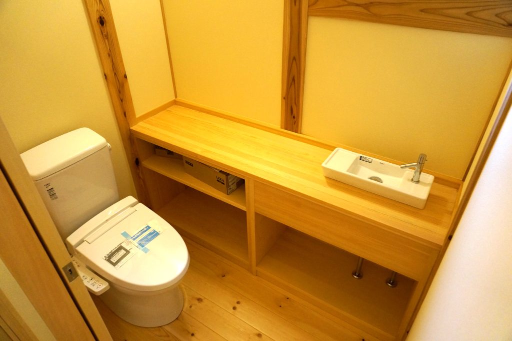 赤松材の無垢フロアに赤松材でカウンター収納。手洗い器を取り付けたひろーいトイレ空間